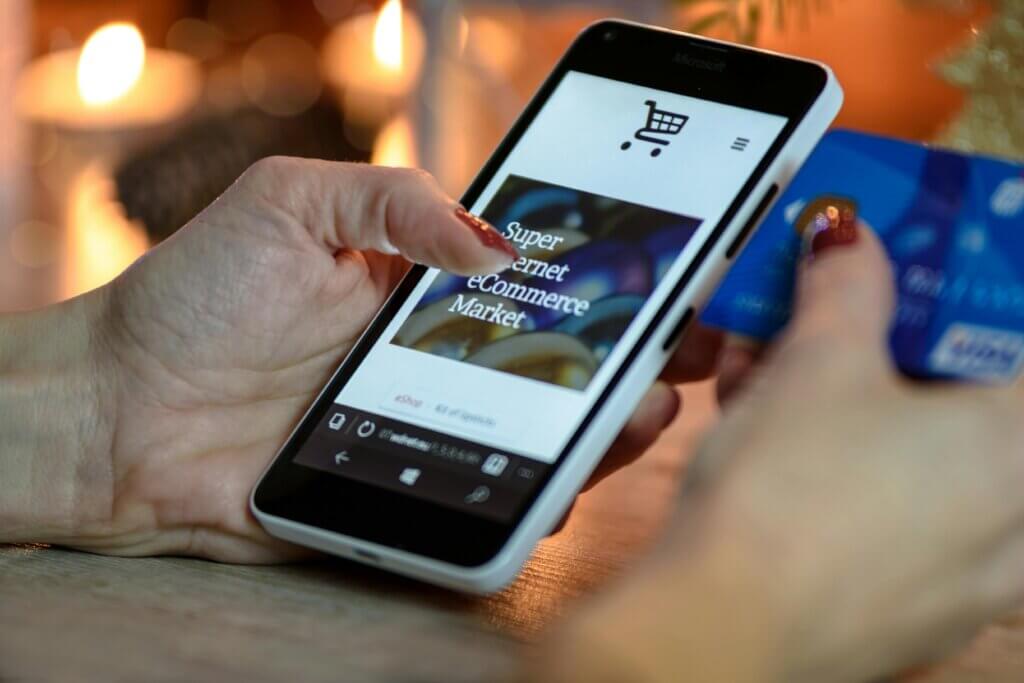 Hand holding a smartphone and a credit card, suggesting online shopping or mobile banking