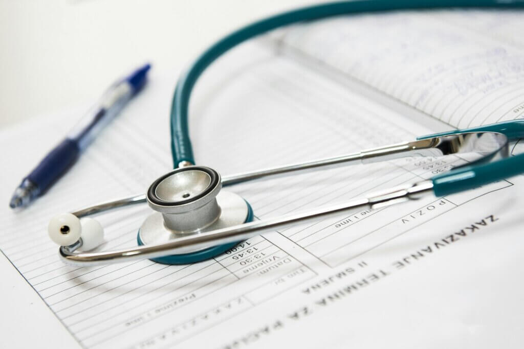 A stethoscope and a pen resting on a white surface.